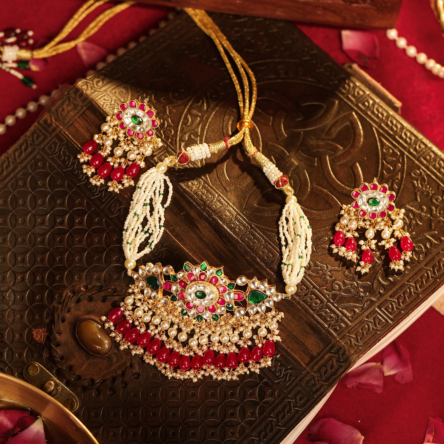 Decorative necklace and earrings on an ornate box with a red background