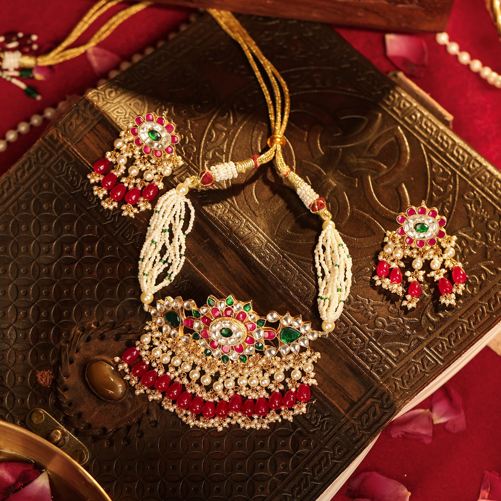 Decorative necklace and earrings on an ornate box with a red background