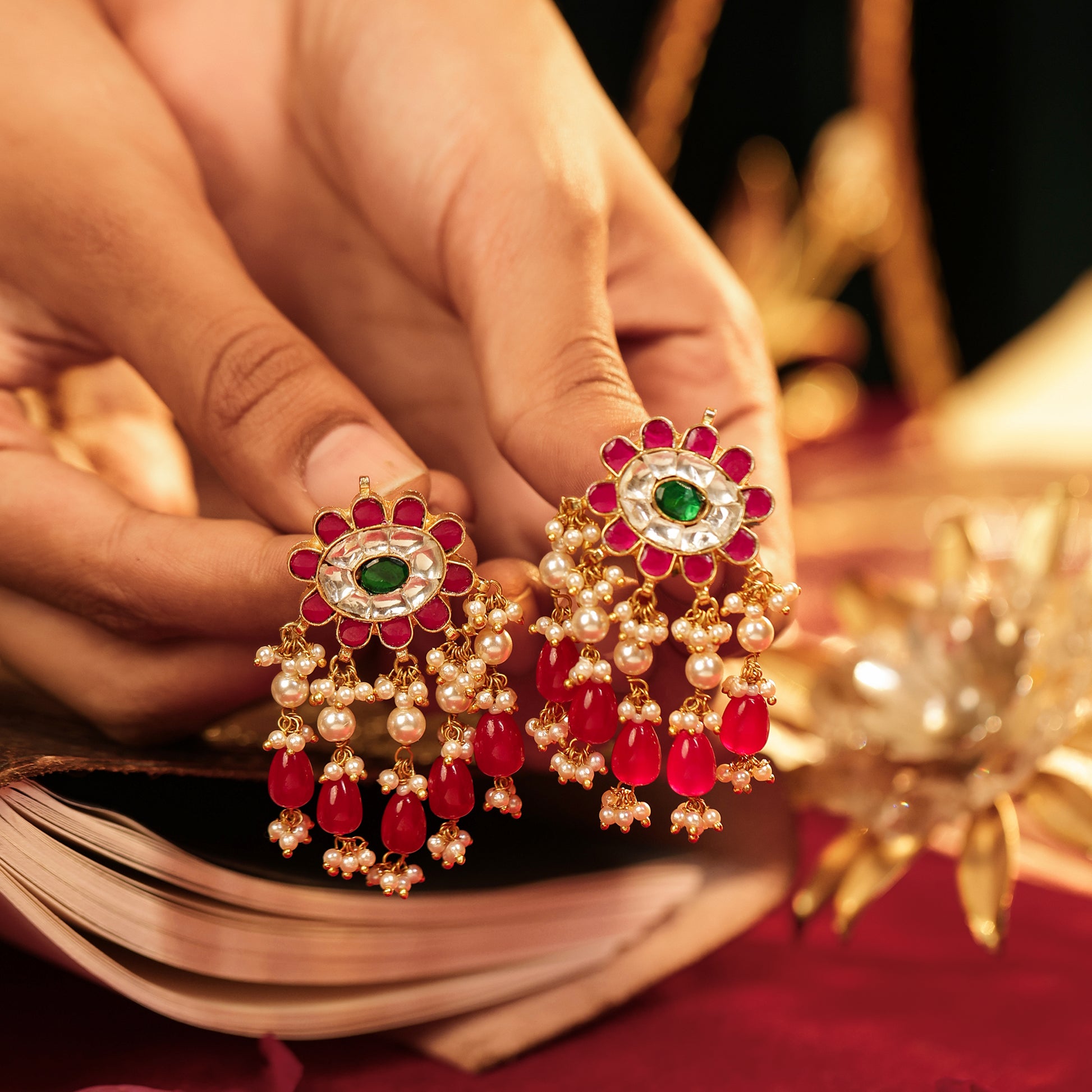 Jewelry set with red and gold earrings held by a hand